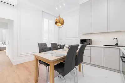 a white kitchen with a wooden table and black chairs at 1 bedroom apartment - Kazimierz- Starowislna 43 in Kraków