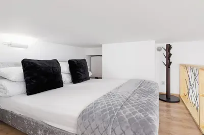 a bedroom with a large white bed with black pillows at Apartment with mezzanine - Radziwiłłowska 27 in Kraków