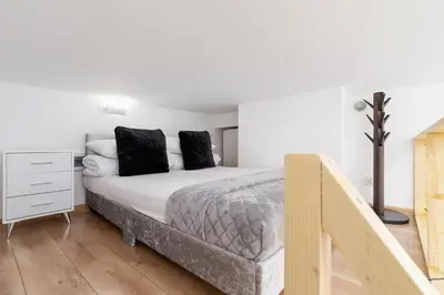 a bedroom with a bed with white sheets and black pillows at Apartment with mezzanine - Radziwiłłowska 27 in Kraków