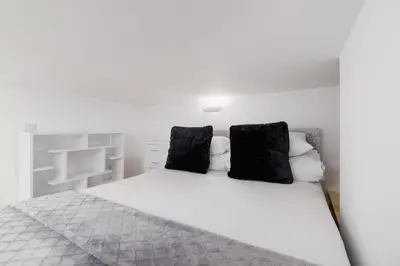 a bedroom with a white bed with black pillows at Apartment with mezzanine - Radziwiłłowska 27 in Kraków