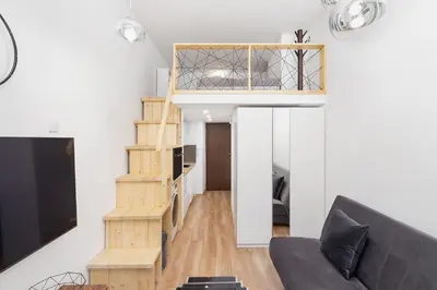 a loft apartment with a staircase and a couch at Apartment with mezzanine - Radziwiłłowska 27 in Kraków