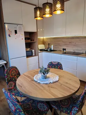a kitchen with a wooden table with chairs and a kitchen with white cabinets at Apartamencik Pod Krokusem in Rabka-Zdroj