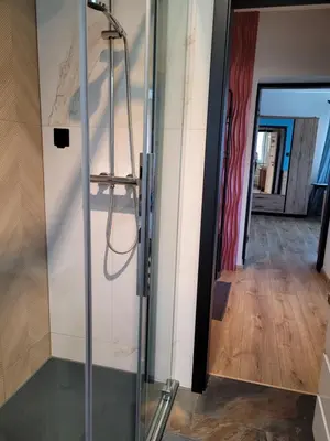 a glass shower in a room with a hallway at Apartamencik Pod Krokusem in Rabka-Zdroj