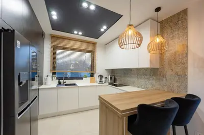 a kitchen with white cabinets and a wooden table at Luksusowy dom z basenem blisko Energylandii, Krakowa i Oświęcimia in Trzebinia