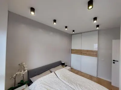 a bedroom with a bed and a wall with lights at Place4You in Kraków