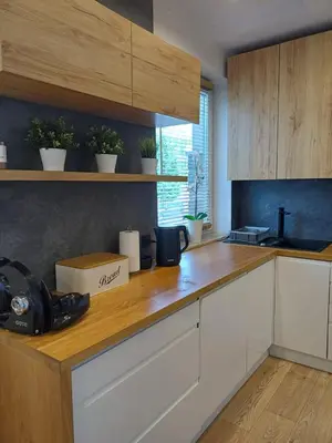 a kitchen with white cabinets and a wooden counter top at Place4You in Kraków
