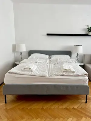 a bed with white sheets and pillows on it at Tomasza Street Main Square Apartment in Kraków