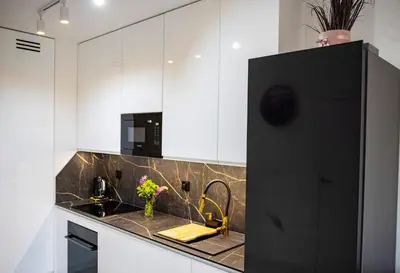 a kitchen with white cabinets and a black refrigerator at Imperial Citi Yes Apartament in Kraków