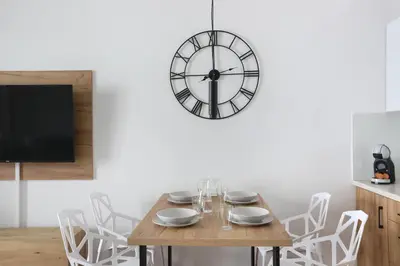 a dining room with a table and a clock on the wall at Luxury Apartment Zablocie WiFi Air Conditioning in Kraków