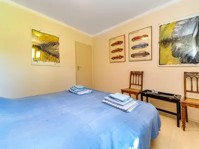 a bedroom with a blue bed and paintings on the wall at Apartment Marcyporęba by Interhome in Marcyporęba