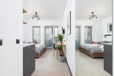 a bedroom with two beds and a living room with windows at Studio apartment - Rakowicka 14 Street in Kraków