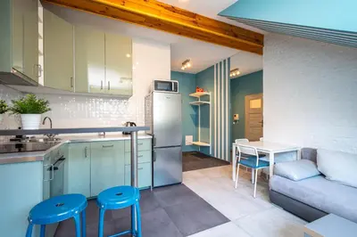a kitchen and living room with a couch and a table at RentPlanet - Apartament Ariańska in Kraków