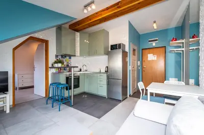 a kitchen and living room with blue walls and a table at RentPlanet - Apartament Ariańska in Kraków