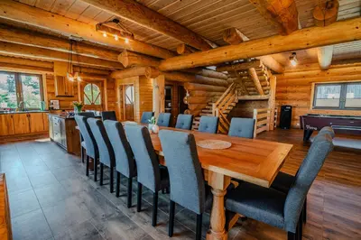 a dining room with a wooden table and chairs at Dom z bali - Serafinówka in Tęgoborze