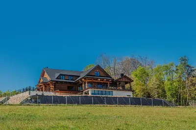 a large wooden house sitting on top of a field at Dom z bali - Serafinówka in Tęgoborze