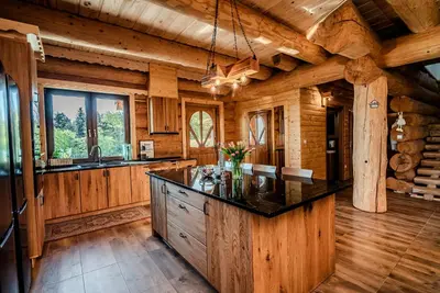 a kitchen with a large island in a log cabin at Dom z bali - Serafinówka in Tęgoborze