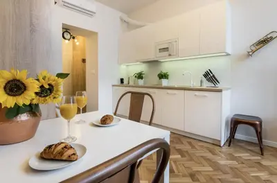 a white kitchen with a table with a vase of sunflowers on it at Studio apartment - Centre of Kraków - Starowiślna 54 in Kraków