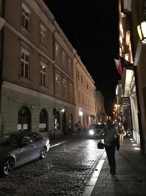 a person walking down a cobblestone street at night at Climatic studio for 2-4 person in Main Square in Kraków