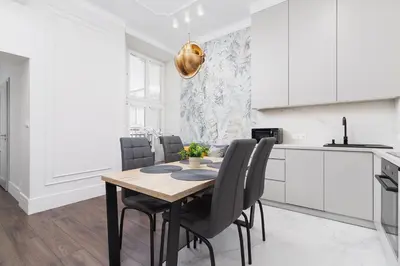 a white kitchen with a wooden table and chairs at Apartment with balcony - Kazimierz- Starowislna 43 in Kraków