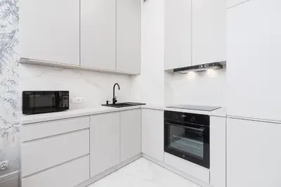 a white kitchen with white cabinets and a microwave at Apartment with balcony - Kazimierz- Starowislna 43 in Kraków