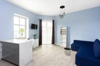 a living room with a blue couch and a table at Pawia Apartments Studio in Kraków