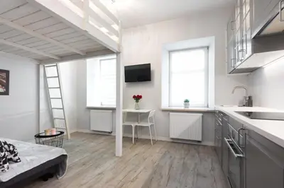 a white room with a loft bed and a kitchen at Pawia Apartments Studio in Kraków