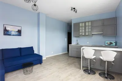 a living room with a blue couch and a kitchen at Pawia Apartments Studio in Kraków