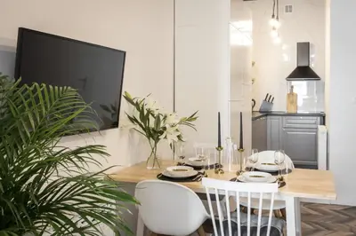 a dining room with a table and two white chairs at Jozefa 20 Street 2 bedroom apartment in Kraków