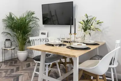 a dining room with a wooden table and white chairs at Jozefa 20 Street 2 bedroom apartment in Kraków