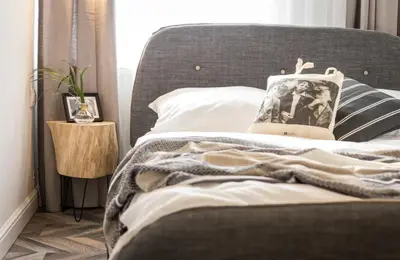 a bed with a gray headboard with a pillow on it at Jozefa 20 Street 2 bedroom apartment in Kraków