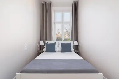 a bedroom with a bed with blue pillows and a window at 3 Bedroom Apartment - Dietla 11 in Kraków