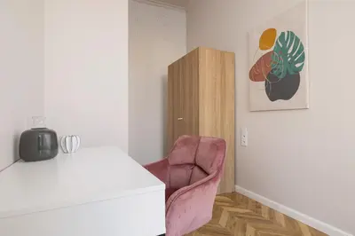 a room with a pink chair and a table at 3 Bedroom Apartment - Dietla 11 in Kraków