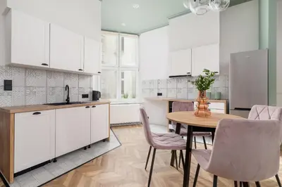 a kitchen with white cabinets and a table and chairs at 3 Bedroom Apartment - Dietla 11 in Kraków