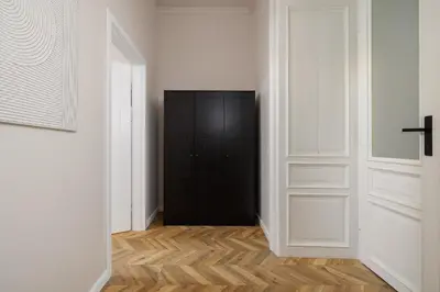 a hallway with a black door and wooden floors at 3 Bedroom Apartment - Dietla 11 in Kraków