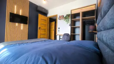 a bedroom with a blue bed and a television at Lema Tauron Arena Two Bedroom Apartment in Kraków