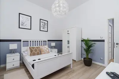a white bedroom with a bed and a potted plant at Dajwór 20 - Dzielnica Żydowska in Kraków