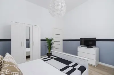 a white bedroom with a bed and a tv at Dajwór 20 - Dzielnica Żydowska in Kraków