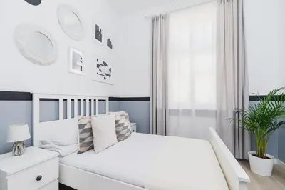 a white bedroom with a white bed and a window at Dajwór 20 - Dzielnica Żydowska in Kraków