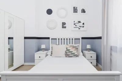 a white bedroom with a large white bed and two night stands at Dajwór 20 - Dzielnica Żydowska in Kraków