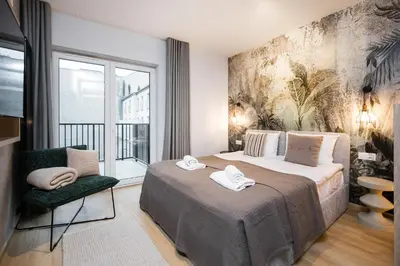 a bedroom with a large bed and a chair at Horizon Apartments Na Dołach - Luxury Apartments near the Vistula River in Kraków