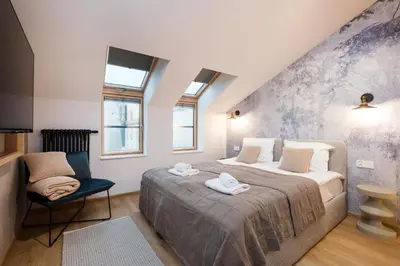 a bedroom with a large bed and a chair at Horizon Apartments Na Dołach - Luxury Apartments near the Vistula River in Kraków