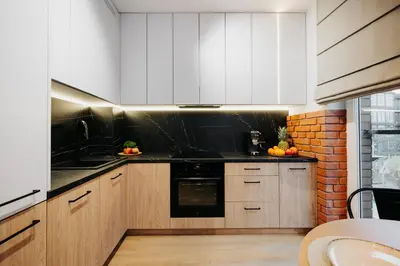 a kitchen with white cabinets and black counter tops at Horizon Apartments Na Dołach - Luxury Apartments near the Vistula River in Kraków