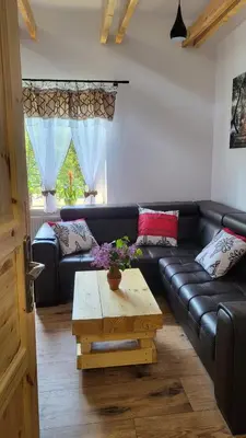a living room with a black leather couch and a coffee table at Stylove Apartamenty in Kocierz Rychwałdzki
