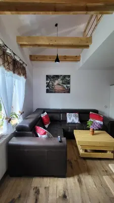 a living room with a black leather couch and a table at Stylove Apartamenty in Kocierz Rychwałdzki
