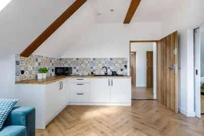 a kitchen with white cabinets and a blue couch at Green Door in Oświęcim