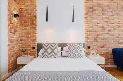 a bedroom with a white bed with a brick wall at Kazimierz District - Dietla 21 street in Kraków
