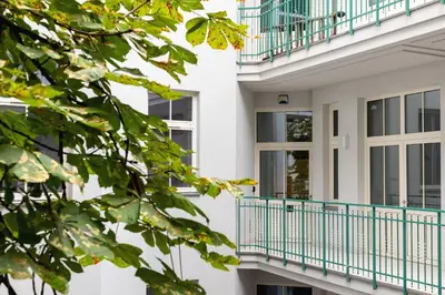 a white building with blue balconies and trees at Kazimierz District - Dietla 21 street in Kraków