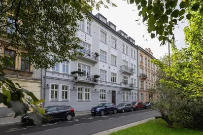 a white building with cars parked in front of it at Kazimierz District - Dietla 21 street in Kraków