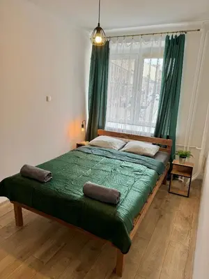a bedroom with a bed with green sheets and a window at Well Apartment in Old Town in Kraków