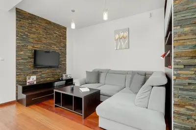 a living room with a white couch and a brick wall at Gamers' Paradise - Modern Apartment with Parking in Cracow by Noclegi Renters in Kraków